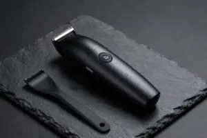 Sleek electric trimmer for body hair with attachments on a wet slate surface