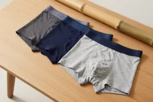 Folded men's bamboo boxer briefs that don't ride up displayed on a wooden surface with bamboo stems