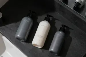 Minimalist bottles of men's face lotion with built-in SPF sitting on a slate bathroom vanity