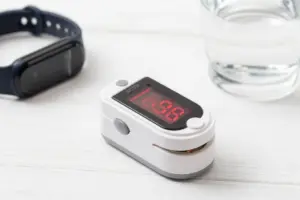 Modern digital fingertip pulse oximeter displaying oxygen readings on a clean desk