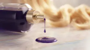 Deep violet purple shampoo bottle on a pastel marble table with blonde hair blurred in the background